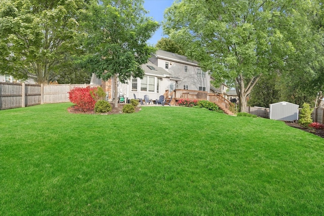 view of yard featuring a wooden deck and a storage unit