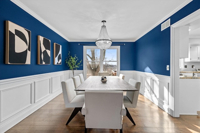 dining space featuring light hardwood / wood-style flooring, ornamental molding, and an inviting chandelier