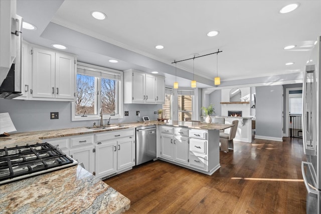 kitchen featuring white cabinets, decorative light fixtures, sink, kitchen peninsula, and stainless steel appliances