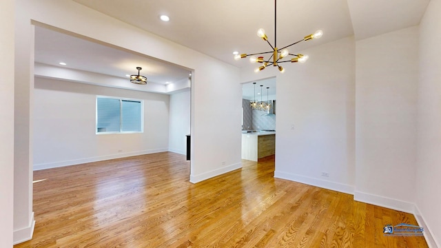 unfurnished room with an inviting chandelier and light hardwood / wood-style flooring