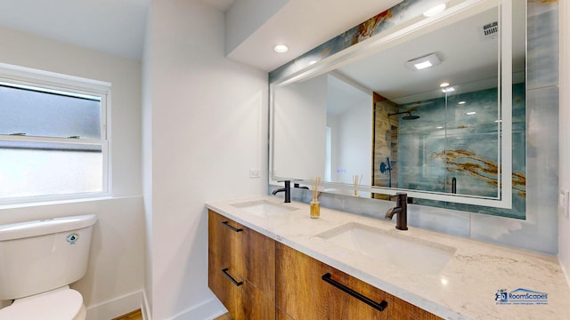 bathroom featuring vanity, toilet, plenty of natural light, and a shower with shower door