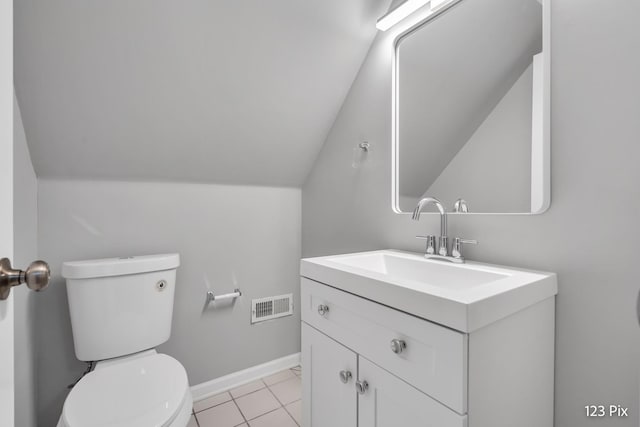 bathroom with tile patterned floors, vanity, toilet, and lofted ceiling