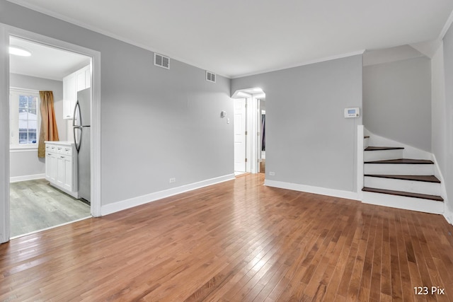 unfurnished living room with light wood-type flooring and ornamental molding