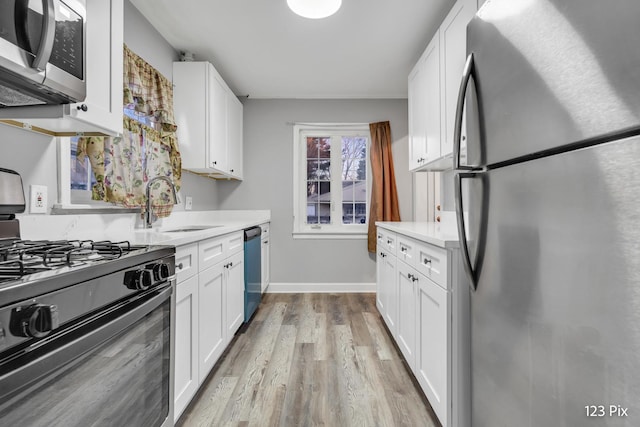 kitchen with sink, white cabinetry, stainless steel appliances, and light hardwood / wood-style flooring