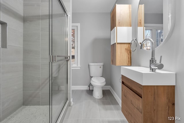 bathroom featuring tile patterned floors, vanity, a shower with shower door, and toilet