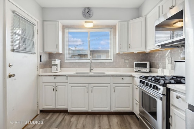 kitchen with a wealth of natural light, white cabinetry, sink, and stainless steel appliances