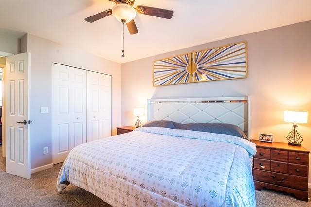 bedroom featuring ceiling fan, light colored carpet, and a closet