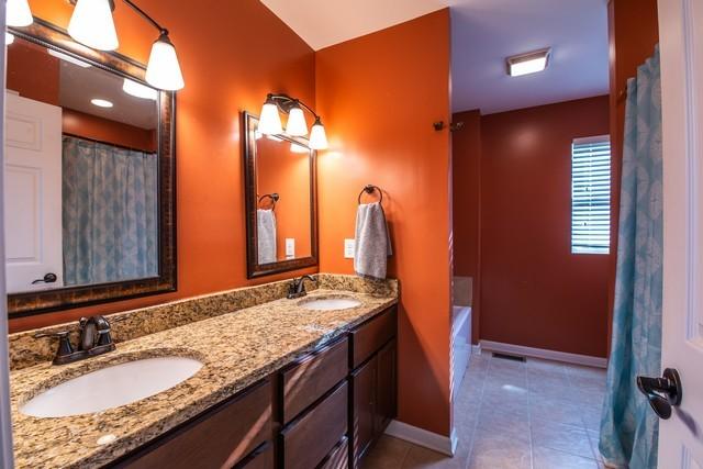 bathroom featuring tile patterned flooring, vanity, and a bath