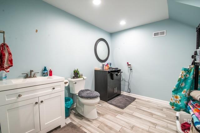 bathroom with vanity, wood-type flooring, lofted ceiling, and toilet