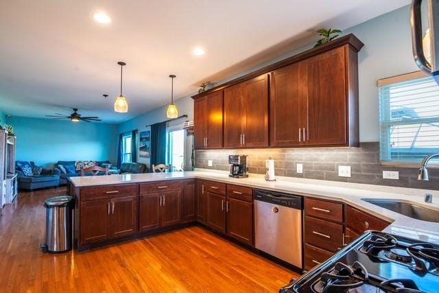 kitchen featuring dishwasher, sink, light hardwood / wood-style flooring, decorative light fixtures, and kitchen peninsula