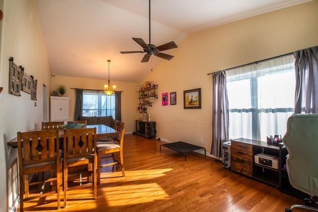 dining room with ceiling fan with notable chandelier, wood-type flooring, and lofted ceiling