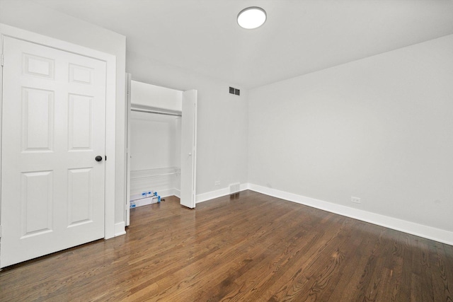 unfurnished bedroom featuring a closet and dark hardwood / wood-style floors