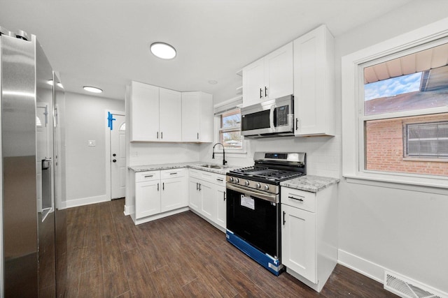 kitchen featuring white cabinets, stainless steel appliances, light stone counters, and dark hardwood / wood-style floors