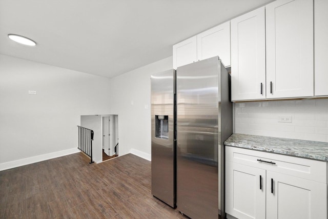 kitchen with stainless steel refrigerator with ice dispenser, backsplash, light stone counters, dark wood-type flooring, and white cabinetry