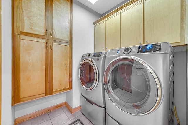 laundry room with cabinets, light tile patterned floors, and washing machine and clothes dryer