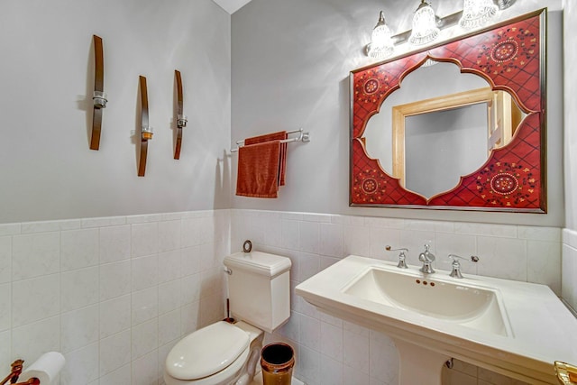 bathroom featuring toilet, tile walls, and sink