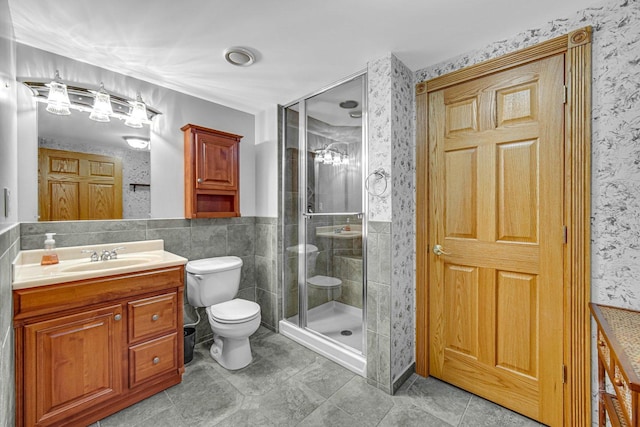 bathroom with vanity, toilet, tile walls, and walk in shower