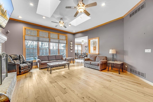 living room featuring a healthy amount of sunlight, a skylight, light hardwood / wood-style flooring, and ornamental molding