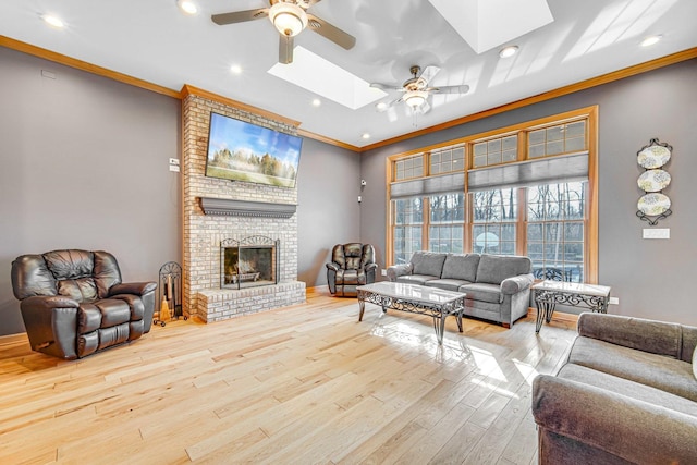 living room featuring a skylight, ceiling fan, ornamental molding, and light hardwood / wood-style floors