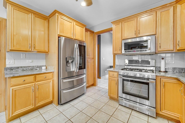 kitchen featuring light stone countertops, light tile patterned floors, appliances with stainless steel finishes, and tasteful backsplash