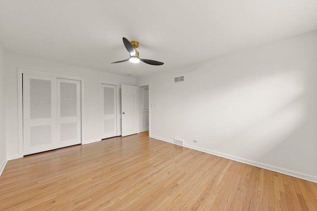 unfurnished bedroom with multiple closets, light wood-type flooring, visible vents, and baseboards