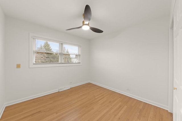 empty room with ceiling fan, light wood finished floors, visible vents, and baseboards