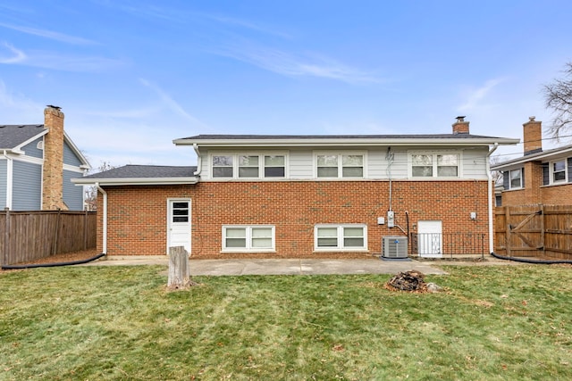 back of property featuring a yard, brick siding, a fenced backyard, and central air condition unit