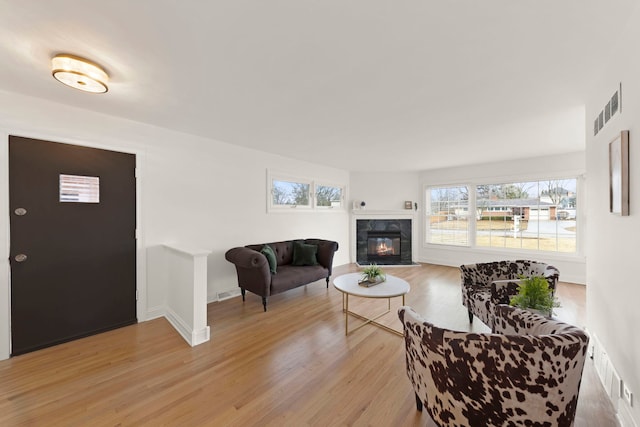 living room with light wood-type flooring, visible vents, and a tile fireplace