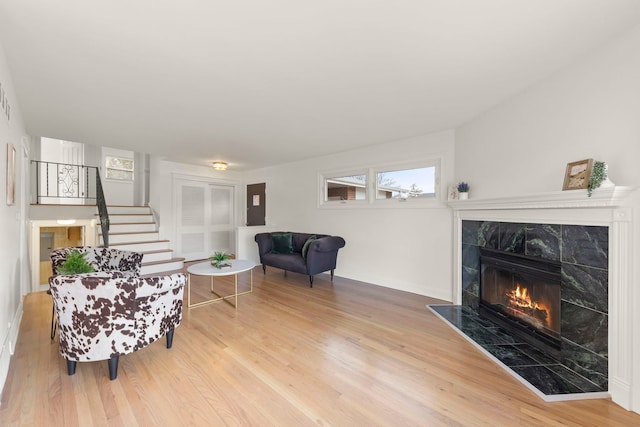 living room featuring stairs, a premium fireplace, and wood finished floors