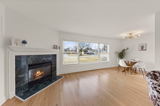 living room with a chandelier, a fireplace, wood finished floors, and baseboards