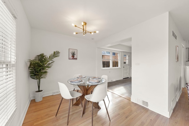 dining space featuring baseboards, light wood-style flooring, visible vents, and an inviting chandelier