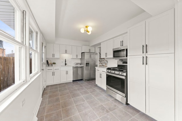 kitchen with decorative backsplash, stainless steel appliances, a sink, and light countertops