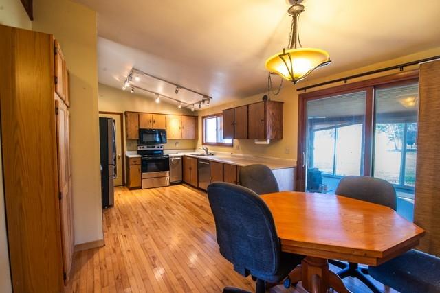 dining space featuring lofted ceiling, light wood-type flooring, and sink