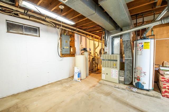 basement featuring electric panel and water heater