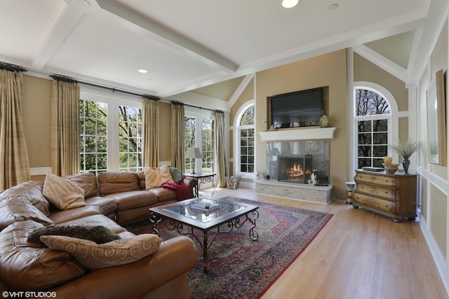 living room featuring lofted ceiling with beams, light wood-type flooring, and a fireplace