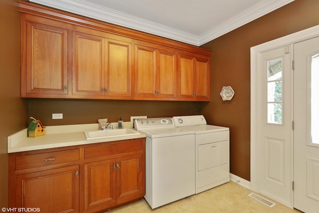 clothes washing area featuring cabinets, ornamental molding, sink, and washing machine and dryer