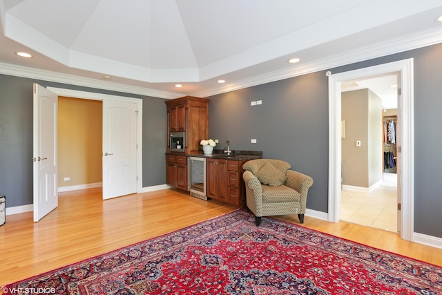 living room with ornamental molding, beverage cooler, and light hardwood / wood-style floors