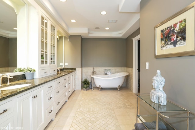 bathroom with tile walls, vanity, a raised ceiling, a bathtub, and tile patterned flooring