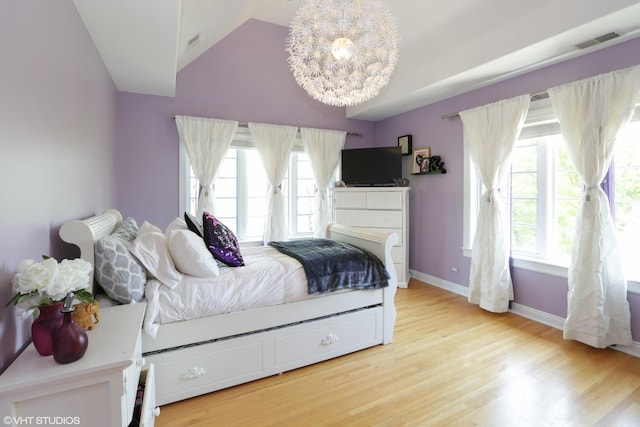 bedroom with multiple windows, light hardwood / wood-style floors, and lofted ceiling