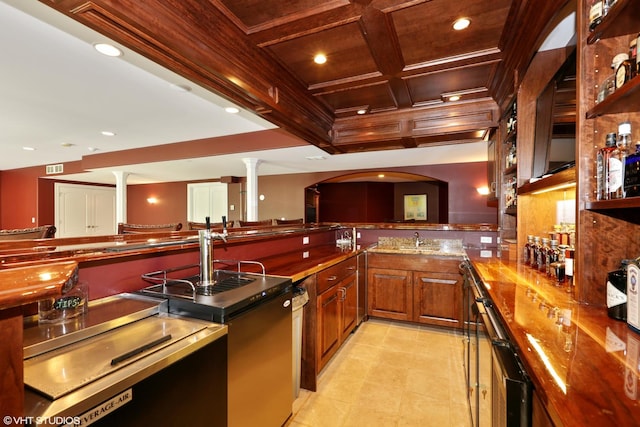 kitchen featuring coffered ceiling, sink, stone counters, beamed ceiling, and decorative columns