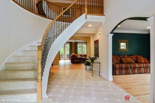 foyer entrance with decorative columns, ornamental molding, hardwood / wood-style flooring, and a high ceiling