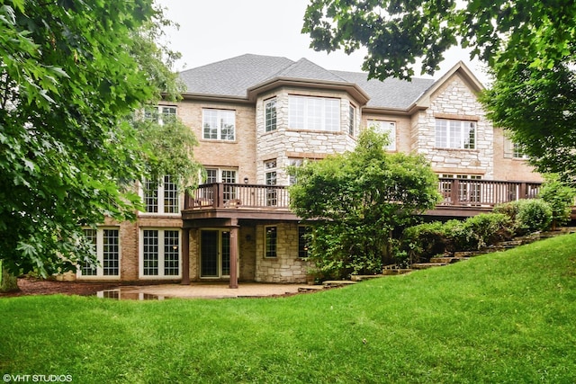 rear view of property featuring a deck, a patio area, and a lawn