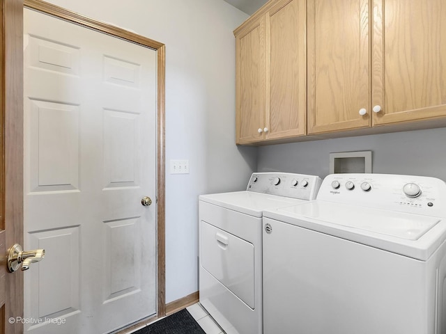 clothes washing area featuring tile patterned floors, washer and dryer, and cabinets