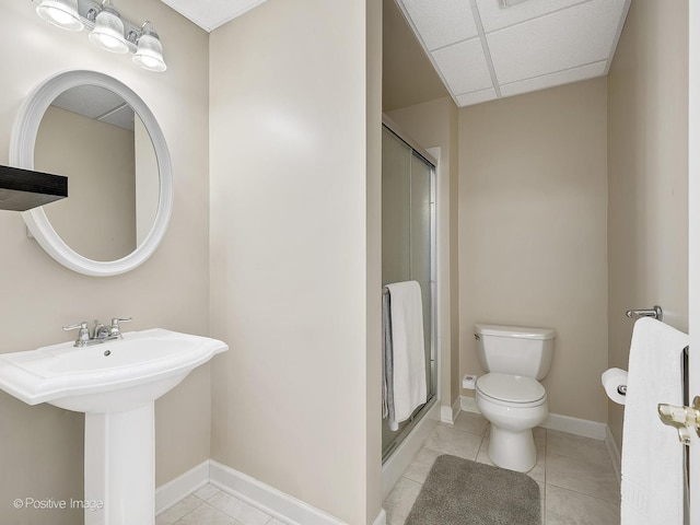 bathroom featuring tile patterned floors, a drop ceiling, a shower with shower door, and toilet