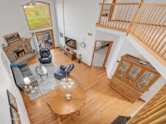 living room with hardwood / wood-style floors, a towering ceiling, and a brick fireplace