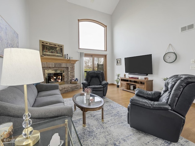 living room with a fireplace, high vaulted ceiling, and hardwood / wood-style flooring