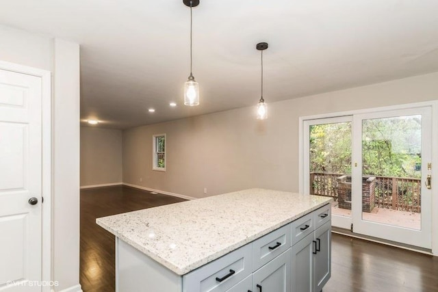 kitchen featuring light stone counters, dark hardwood / wood-style floors, pendant lighting, gray cabinets, and a kitchen island