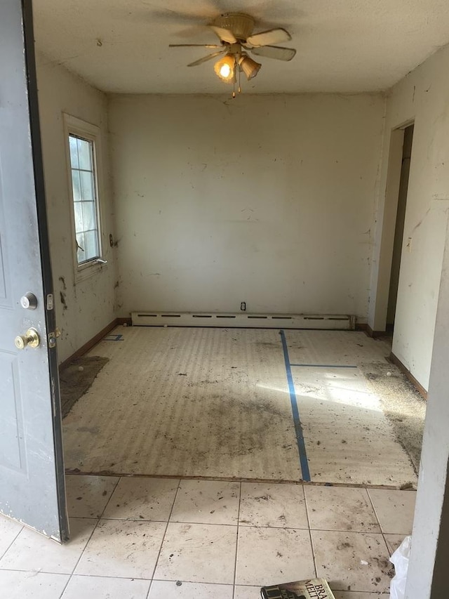 empty room featuring ceiling fan and a baseboard heating unit