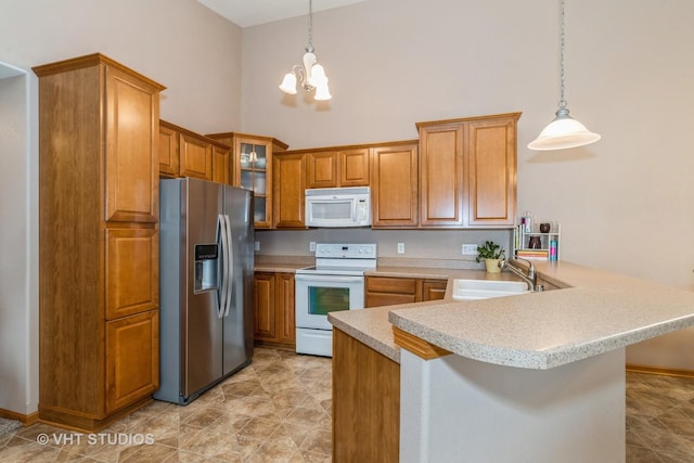 kitchen with kitchen peninsula, white appliances, decorative light fixtures, and sink