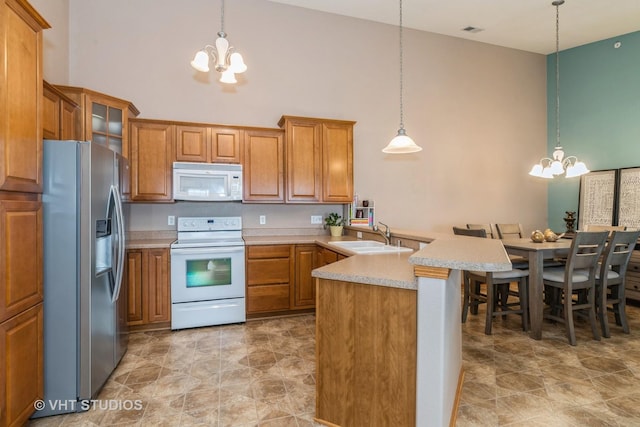 kitchen with kitchen peninsula, white appliances, hanging light fixtures, and a chandelier